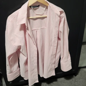 Röd- och vitrandig skjorta från Zara - Snygg röd- och vitrandig skjorta från Zara med klassisk krage och långa ärmar. Perfekt för en stilren look. Skjortan har en avslappnad passform och är tillverkad i ett lätt och bekvämt material.