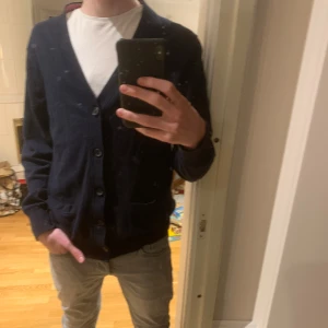 Mörkblå cardigan från Tommy Hilfiger - Säljer nu en gosig kofta ifrån märket Tommy Hilfigher. Plagget är knappt använt, och har därför inga synliga defekter. Tröjan är i storlek L men passar även de med M. Modellen är ca 190cm. Säljer för 329kr, nypris ca 1000 kr. Priset är inte hugget i sten.