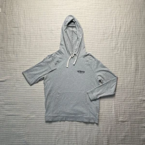 Grå hoodie från Lexington - Säljer en stilren grå hoodie från Lexington med broderad logga på bröstet. Tröjan har en justerbar huva och en praktisk magficka. 