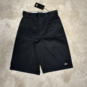 Dickies - Snygga svarta shorts från Dickies i loose fit. Perfekta för en avslappnad stil med praktiska fickor och dragkedja. Märkeslogga synlig på sidan. Passar bra till både vardag och fritid.