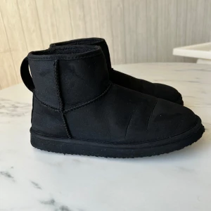 Svarta boots - Säljer ett par svarta boots med rund tå och dragflik bak. De är tillverkade i ett mjukt material och har en robust sula för bra grepp. 