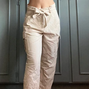 Beige cargobyxor med knytband - Snygga beige cargobyxor med hög midja och knytband. Byxorna har praktiska fickor på sidorna och en loose passform som ger en avslappnad stil. Perfekta byxorna i vardagen.🤍🤍Aldrig använda