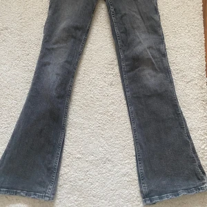 Grå jeans från Gina Tricot - Snygga grå jeans från Gina Tricot med bootcut-stil. De har en klassisk femficksdesign och en dragkedja med knapp framtill. Perfekta för en avslappnad look.