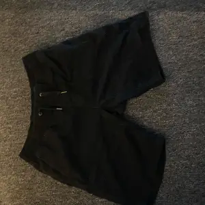 Snygga svarta shorts med snörning i midjan. Perfekta för en avslappnad stil. De har en klassisk design med fickor bak och en bekväm passform.
