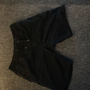 Svarta shorts med snörning mjukis/denim - Snygga svarta shorts med snörning i midjan. Perfekta för en avslappnad stil. De har en klassisk design med fickor bak och en bekväm passform.
