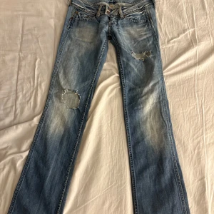 Blå lågmidjade jeans från pepe - Snygga blå jeans från pepe med slitningar på framsidan. Lågmidjade i storlek W26 L34