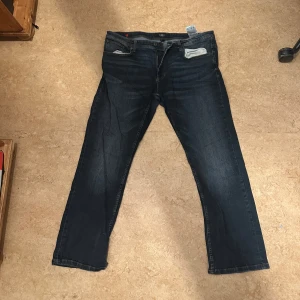 Mörkblå jeans från Smog - Säljer ett par mörkblå jeans från Smog. De har en klassisk femficksdesign med knapp och dragkedja framtill. Perfekta för en avslappnad stil.