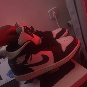 Svartvita Nike Air Jordans - Snygga svartvita Nike Air Jordans med klassisk design. Skorna har en hög siluett med snörning och det ikoniska Air Jordan-märket på sidan. Perfekta för en stilren look.