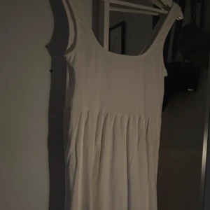 Vit klänning från MNG - Säljer en stilren vit klänning från MNG i storlek XS. Klänningen har en enkel design med ärmlös stil och en lätt volangdetalj vid fållen. Perfekt för varma dagar och kan enkelt stylas upp eller ner beroende på tillfälle.