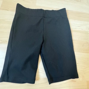Svarta ribbade shorts från lager 157 - Snygga svarta ribbade shorts från Zara. Perfekta för en avslappnad stil med en bekväm passform. De är knälånga och har en elastisk midja för extra komfort.