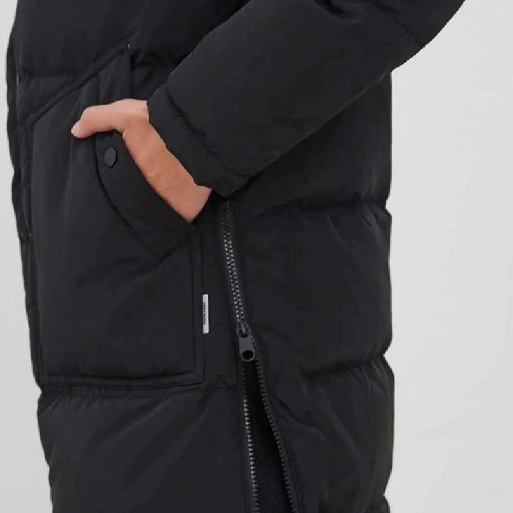 Säljer en svart dunjacka från vero Moda med dragkedja och stora fickor framtill. Jackan har en huva och långa ärmar, perfekt för kalla dagar. Den är både stilren och funktionell. Köpt för 1600kr men säljer för 550kr.. Takit.