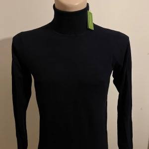 Mörkblå polotröja från Gianni Feraud - Säljer en stilren mörkblå polotröja från Gianni Feraud . Tröjan har en klassisk design med långa ärmar och en hög polokrage. Perfekt för en elegant och bekväm look. Begränsad upplaga, så passa på att köpa nu! Oanvänd i nyskick 