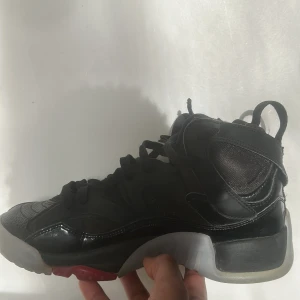 Svarta Nike Air Jordans - Snygga svarta Nike Air Jordans med klassisk design och röd detalj på hälen. Skorna har snörning och en robust sula för extra komfort. Perfekta för dig som vill ha en stilren look med en sportig touch.