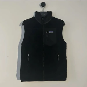 Patagonia Väst  - Säljer en svart fleeceväst från Patagonia med dragkedja och praktiska fickor. Perfekt för kyliga dagar och har en stilren design med en liten logga på bröstet. Storlek L men passar M. Hör gärna av er vid flera frågor eller funderingar! 
