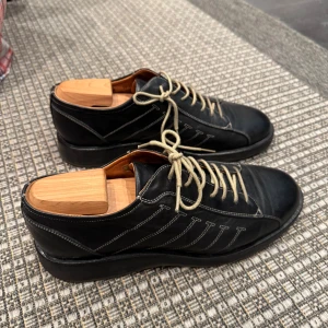 Johnston & Murphy skor, mörk marinblå nyskick - Johnston & Murphy skor, nyskick i mörkt marinblått. Skinnskor med snörning. Tillhörande skoblock medföljer.  Storlek 10 (43).