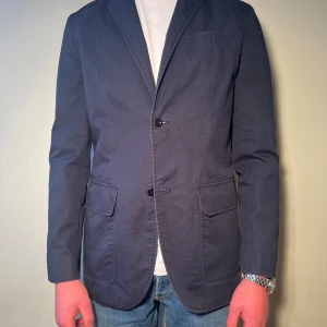 Mörkblå kavaj från Ralph Lauren - Snygg mörkblå kavaj med klassisk design och två knappar framtill. Perfekt för en stilren look. Storlek S men sitter som M. 