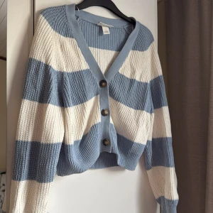 Randig kofta - Säljer en snygg randig kofta från Monki i blått och vitt. Koftan har stora knappar framtill och är ribbad för en skön passform. Perfekt för en avslappnad stil.