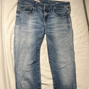 Replay jeans - Snygga ljusblå jeans från replay med klassisk femficksdesign och diskreta slitningar. De har en dragkedja och knapp framtill samt dekorativa sömmar på bakfickorna. Perfekta för en avslappnad stil.