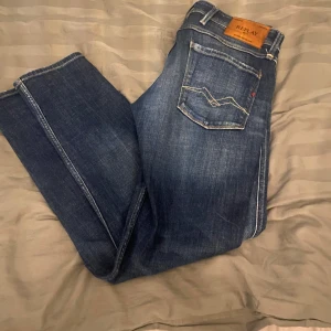 Blå jeans från Replay - Snygga blå jeans från Replay i modellen Anbass. De har en klassisk femficksdesign med dragkedja och knapp. Perfekta för en avslappnad stil. Ny pris för just dessa ligger runt 2000kr