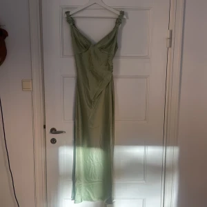 Pistagefärgad långklänning från ADOORE - Elegant pistagefärgad långklänning från ADOORE med smickrande passform och breda axelband. Perfekt för speciella tillfällen med sin stilrena design.