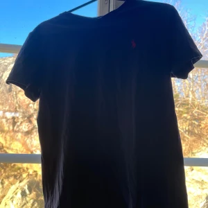 Marin blå Ralph lauren T-shirt - Säljer nu denna marin blå Ralph lauren T-shirt med röd logga på, säljer denna eftersom jag inte andvänder den längre. Köpte för något år sedan på kidsbrandstore så den är såklart äkta. ❤️Skriv för mer frågor eller funderingar 🥰