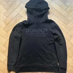 Svart hoodie från Dondup - Säljer en svart hoodie från Dondup med texten 'Unconventional Clothing Established in 1999' på bröstet. Tillverkad i Italien, perfekt för en avslappnad stil. Hoodien har långa ärmar och en klassisk huva. Storlek M passar L. 💯👦🏿