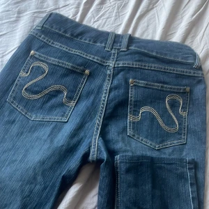 Blå jeans från KappAhl - Snygga blå jeans från KappAhl med dekorativa sömmar på bakfickorna. Klassisk femficksmodell med knapp och dragkedja framtill. Perfekta för en avslappnad stil. 