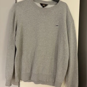 Grå sweatshirt från Lee - Säljer en stilren grå sweatshirt från Lee i storlek M. Tröjan har en klassisk design med rund hals och långa ärmar. 