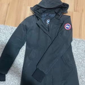 Victoria canada goose jacka dam - Pris kan diskuteras!!Säljer en svart parkajacka från Canada Goose med huva och lång ärm. Jackan har en dragkedja framtill och är quiltad på insidan för extra värme. Perfekt för kalla dagar!