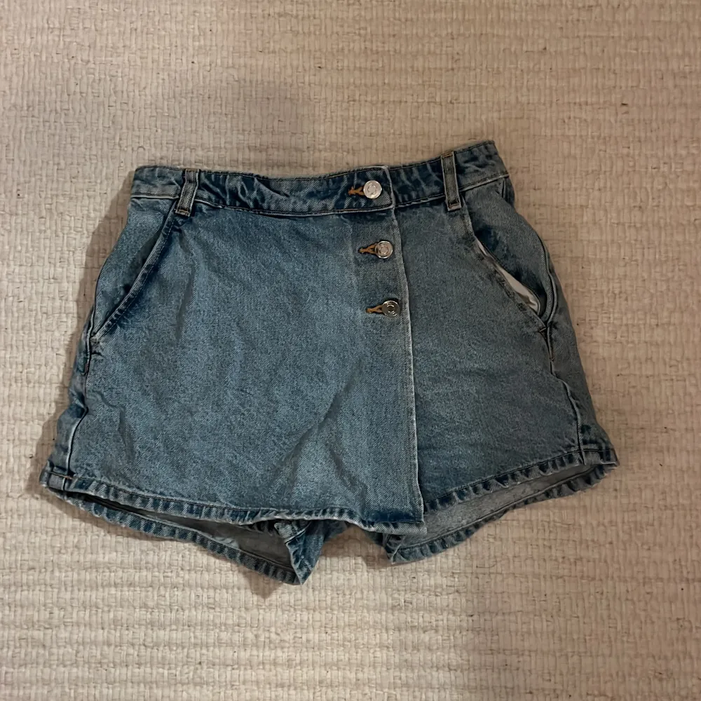 Säljer ett par snygga blå jeansshorts från Zara i storlek XS. De har en högmidjad passform med tre knappar framtill och två bakfickor. . Shorts.