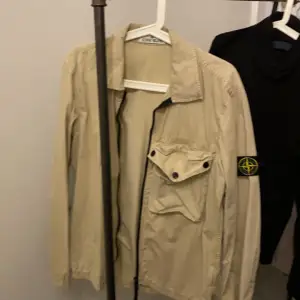 Säljer en snygg beige overshirt jacka från Stone Island. Den har en klassisk design med dragkedja