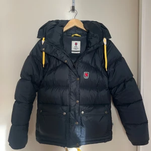 Fjällräven jacka - Nyskick! - Svart Fjällräven jacka i storlek XS modell EXPEDITION DOWN LITE JACKET W Dam.  Inga defekter, nyskick skick utan några som helst anmärkningar. Inga sminkfläckar, spån i fickor osv, som ny! Kvitto finns. Köpt från Naturkompaniet för 7000kr.  (+frakt)