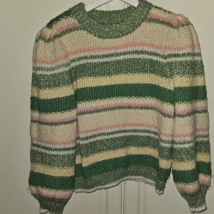 Stickad tröja nytt  - Nytt Snygg randig tröja med puffärmar och trekvarts. Tröjan är i en härlig färgkombination med grönt, rosa ,vitt och gult. Nypris 500 kr