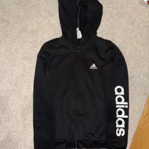 En svart adidas hoodie med dragkedja. Storlek S.