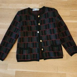 Svart och röd rutig jacka Busnel  - Säljer en snygg svart och röd rutig jacka från Busnel. Den har guldknappar framtill och långa ärmar. Perfekt för höst och vinter med sitt varma ullmaterial. Jackan har en klassisk stil med två fickor fram. Passar både till vardags och lite finare tillfällen. Passar stl XS-S