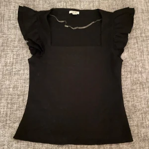 Svart topp från Amisu - Läs info 🎀Säljer en snygg svart topp från Amisu. Toppen har korta volangärmar och en fyrkantig urringning som ger en stilren look. Perfekt för både vardag och fest! 🖤 Känns inte som L! Använd en gång 