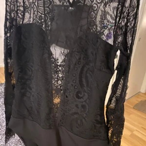 Långärmad spetsbody från H&M - Säljer en elegant svart spetsbody från H&M i storlek M. Den har långa ärmar och ett vackert spetsmönster som ger en lyxig känsla. Perfekt för festliga tillfällen eller en utekväll. Den är både bekväm och stilren, och kan enkelt matchas med olika outfits.