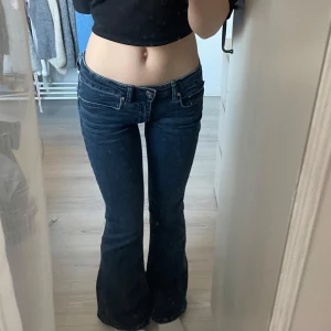 Mörkblå bootcut jeans - Säljer ett par snygga mörkblå bootcut jeans i mycket bra skick. De är lågmidjade och har en klassisk femficksdesign med knappar och dragkedja fram. Perfekta för både vardag och fest! Bara testade, helt nya. Lite korta på mig som är 165cm