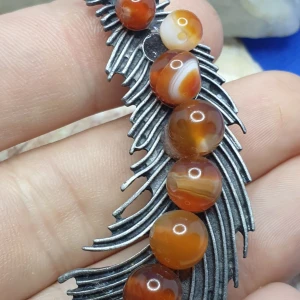 Brosch  / Hänge  - Vacker Fjäder med ädel/halvädelstenar  - En brosch föreställande en Fjäder, storlek ca 7x2.5cm.  Antiksilverfärgad metall med vacker ytstruktur och ädel/halvädel stenar. 