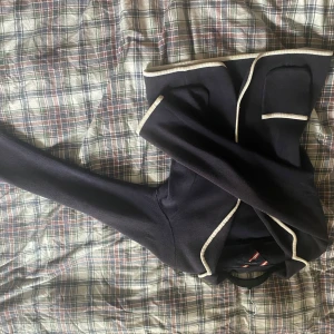 Mörkblå kofta med vita detaljer - Säljer en snygg mörkblå kofta med vita kanter. Perfekt för höst och vår, med långa ärmar och en klassisk look. Den är i mycket bra skick och passar både till vardags och lite finare tillfällen. Från Tommy Hilfiger i storlek L men passas även M