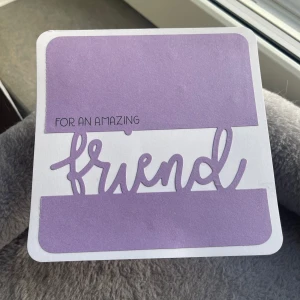 Handgjort kort  - Ett superfint handgjort kort i lila och vitt med texten 'For an Amazing Friend' på framsidan. Inuti finns söta moln och en kanin med texten 'Somebunny is Thinking of You'. Perfekt för att visa uppskattning till en vän! Kortet har rundade hörn och en söt kattillustration på baksidan.