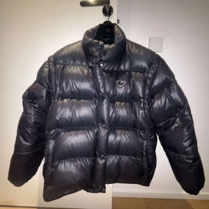 Prada Re-Nylon Convertible Down Jacket - Säljer en Prada Prada Re-Nylon convertible down jacket som är perfekt nu till vintern. Jackan är i väldigt fint skick. Storleken är 42 vilket motsvarar M och är slutsåld överallt. Nypriset ligger på 25.000:-