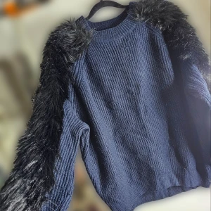 Mörkblå stickad tröja med fuskpälsärmar - Supercool mörkblå stickad tröja med fluffiga fuskpälsdetaljer på ärmarna. Storlek L/XL. Perfekt för dig som är frussen. 🖤 Tröjan är använd och lite nopprig på visda ställen, men har inga andra defekter. 