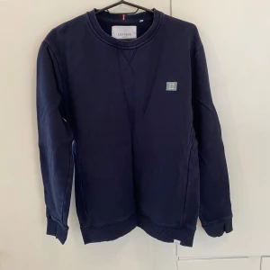 Mörkblå tröja från Les Deux - Säljer en snygg mörkblå tröja från Les Deux i storlek S. Tröjan har långa ärmar och en liten logga på bröstet. Perfekt för både vardag och fest. Den är i bra skick och superbekväm att ha på sig!