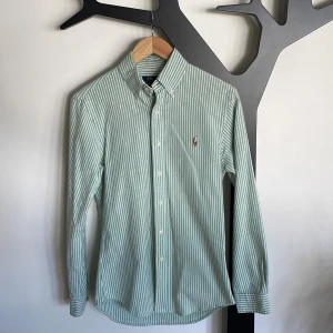 Ralph Lauren Skjorta - Grönvit-randig skjorta från Ralph Lauren i storlek slim fit S. Jättesnygg skjorta som endast använts ett fåtal gånger, skick 9,5/10. Nypris 1795kr.