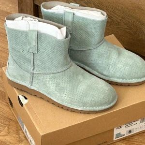 Ljusblå UGG boots - Säljer ett par supermysiga ljusblå UGG boots i mocka. De har en klassisk design med rund tå och en bekväm sula. Perfekta för att hålla fötterna varma under hösten och vintern. De är i storlek 6 och kommer i originalkartong. Helt nytt 