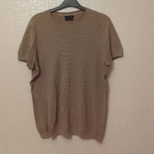 Beige kortärmad tröja från Massimo Dutti - Säljer en stilren och bekväm beige tröja från Massimo Dutti. Den är gjord av exklusiv bomull och har en fin textur som ger en lyxig känsla. Perfekt för både vardag och lite finare tillfällen. Tröjan har korta ärmar och en rund halsringning.