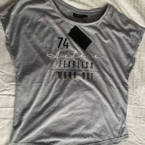 Oanvänd grå tränings t-shirt  - Ny grå träning tröja från Pine Ridge i storlek S. I ett super mjukt material. Tryck med texten '74 Active Fearless Work Out' på framsidan. Tröjan är kortärmad och har en rund halsringning.