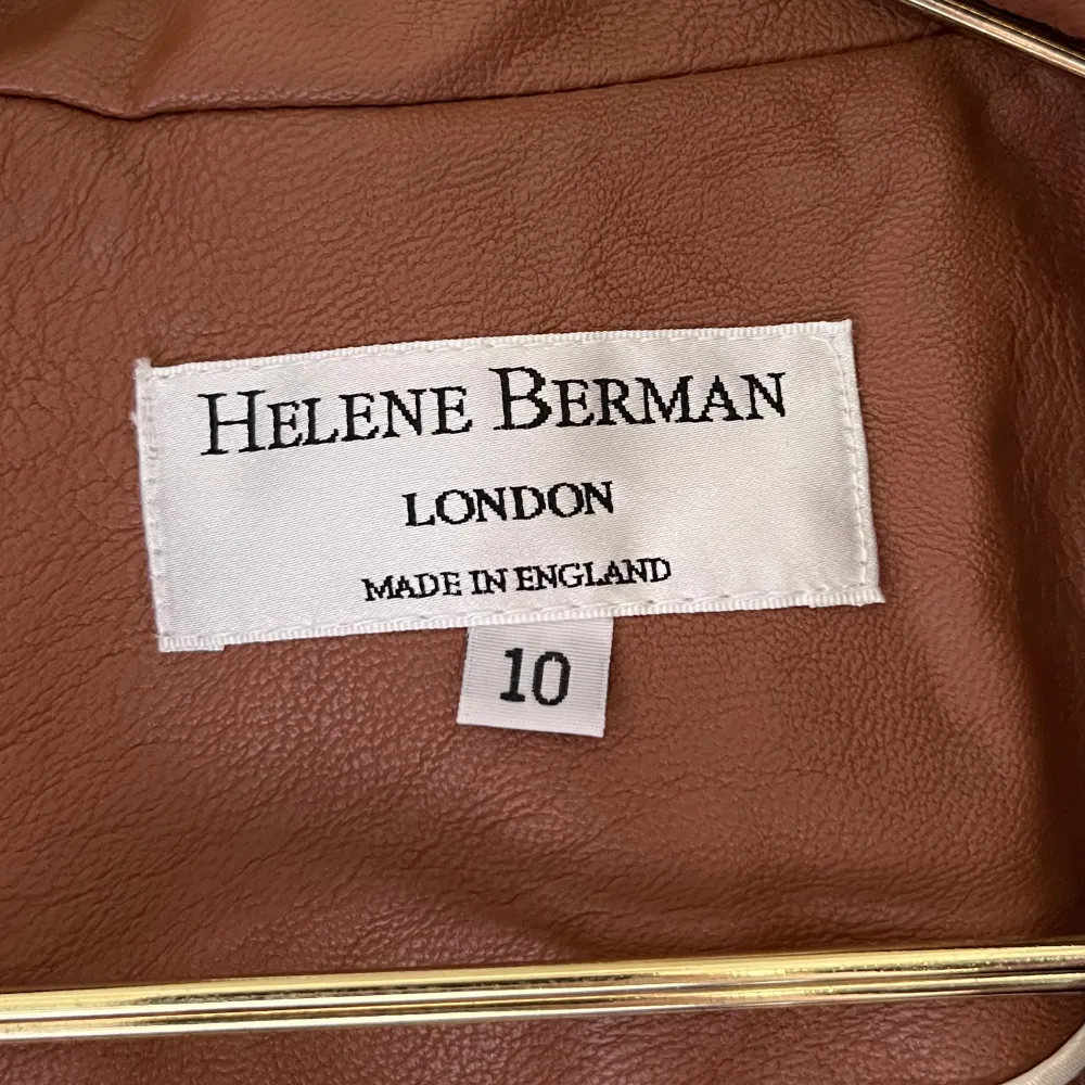 Trenchcoat i brun läderimitation från Helene Berman. Storlek 10 (38). Köpt second hand, använd en gång av förra ägaren, aldrig använd av mig. Mycket fint skick, ser ut som ny!. Jackor.