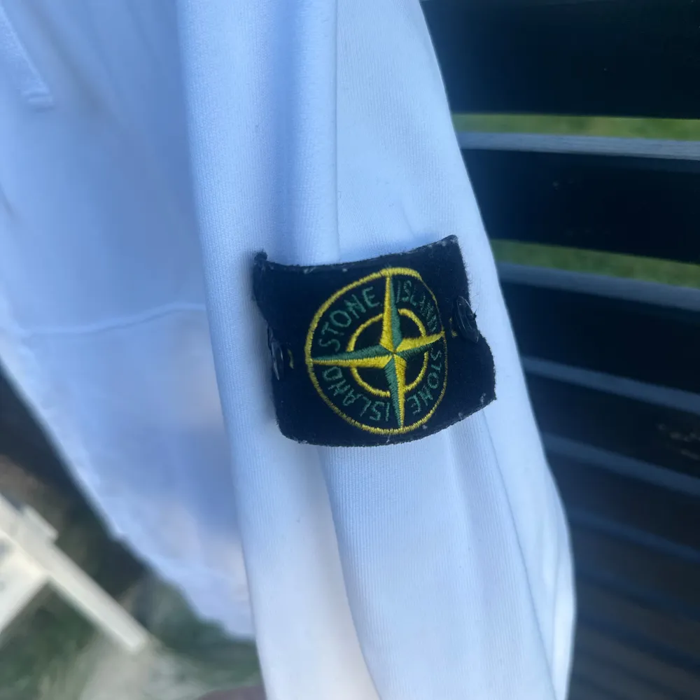 Säljer en snygg vit hoodie från Stone Island. Den har en klassisk design med en stor ficka fram och en justerbar huva med dragsko. Märkets ikoniska patch sitter på ärmen. Perfekt för en stilren och avslappnad look!. Tröjor & Koftor.